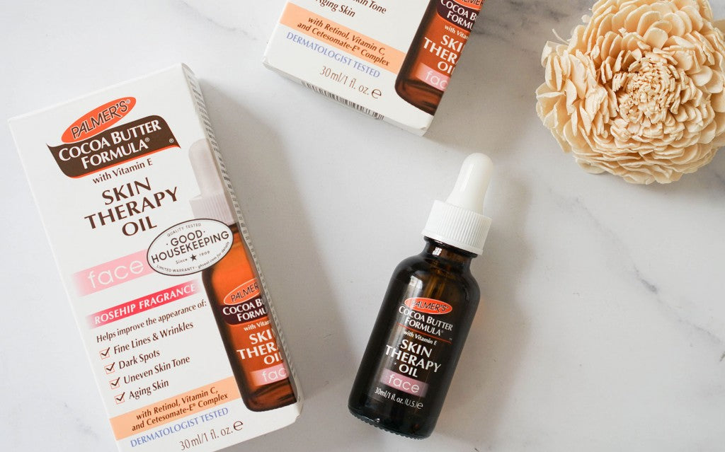 Palmer's Cocoa Butter Formula Skin Therapy Oil Face, a retinol and Vitamin C facial moisturiser oil, on a table with its carton.