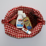Red and white checkered bag with Palmers Cocoa Butter travel products on a light gray background