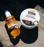 Palmer's Brazilian Coco Firming Body Oil bottle and Whipped Body Cream jar on a stone surface.