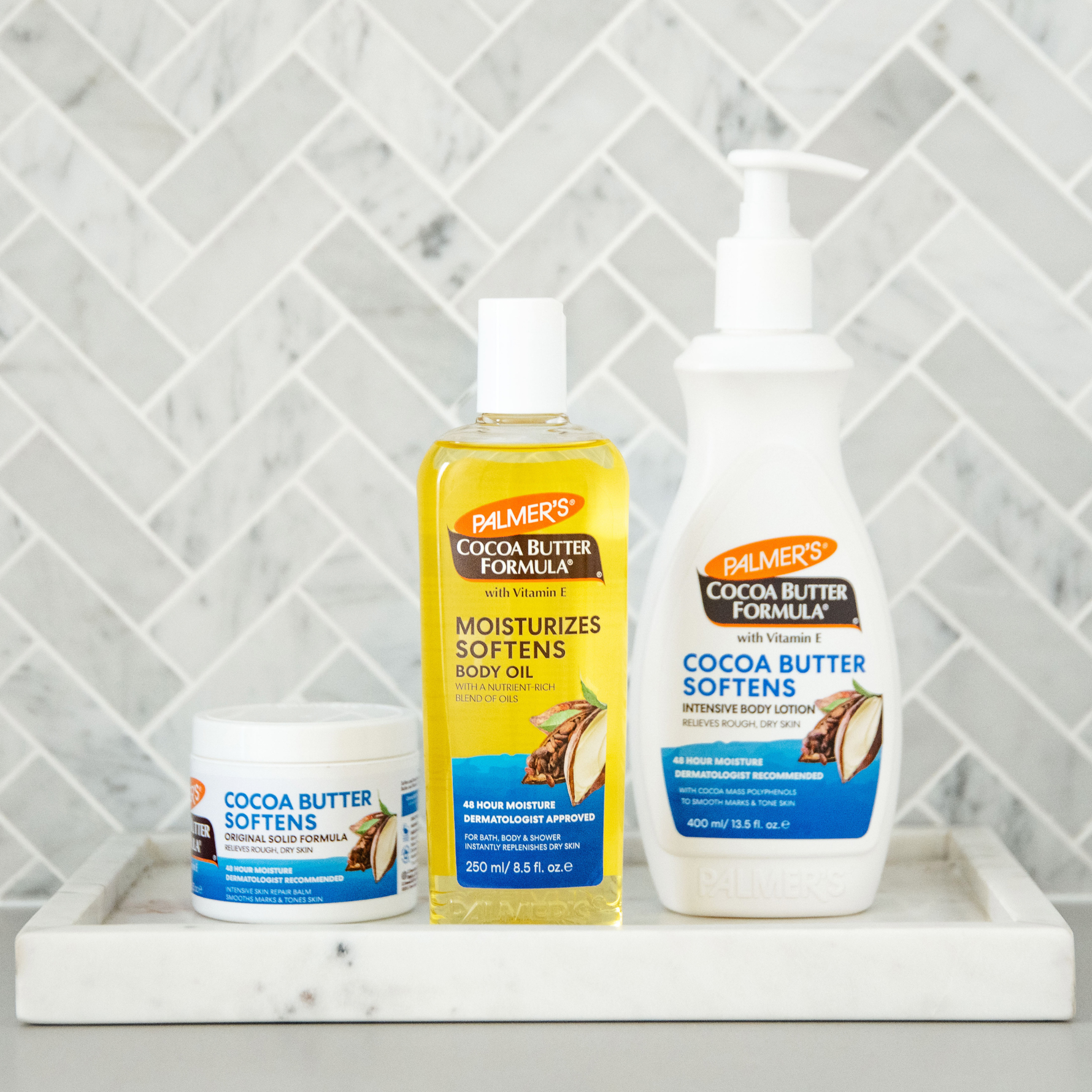 Palmer's Cocoa Butter Formula products on a marble surface with a tiled wall background