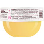 Close-up of the back of a round container showing a white label with black text, a barcode, and a yellow circular graphic at the bottom. The label includes product details such as scent notes, ingredients and directions.
