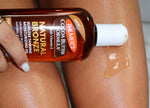 Bottle of Palmer's Cocoa Butter Formula Natural Bronze tanning oil applied to skin.