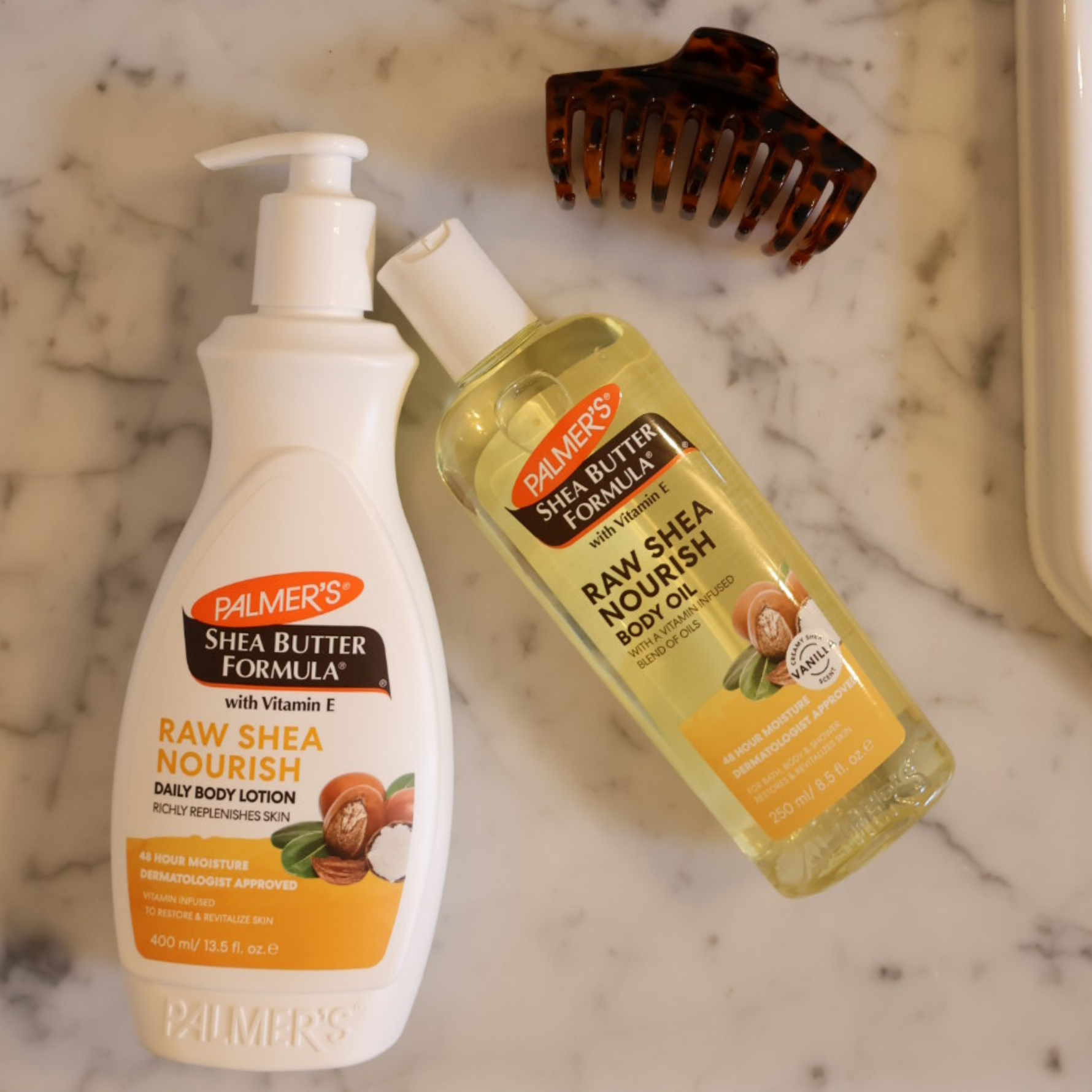 Palmer's Shea Butter Formula body lotion and body oil on a marble surface with a comb.