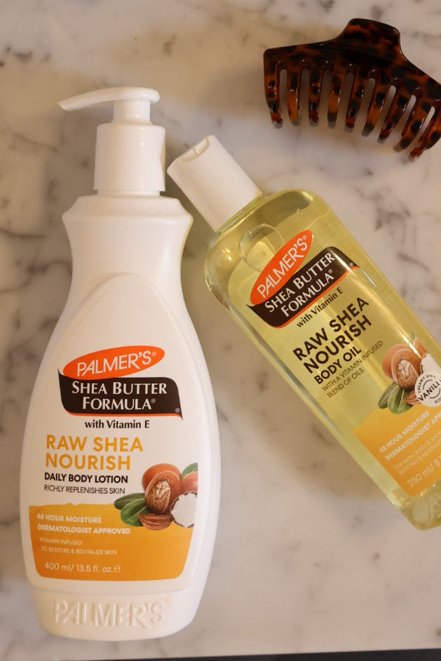 Two bottles of Palmer's Shea Butter Formula products on a marble surface with a comb in the background.