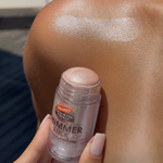Hand holding Palmer's shimmer stick next to shoulder with shimmer applied