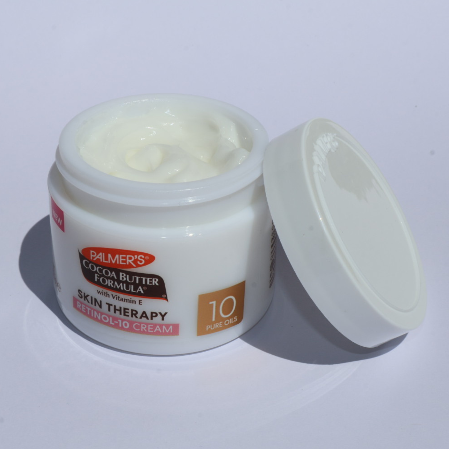 Open jar of Palmer's Cocoa Butter Formula skin therapy cream on a white background