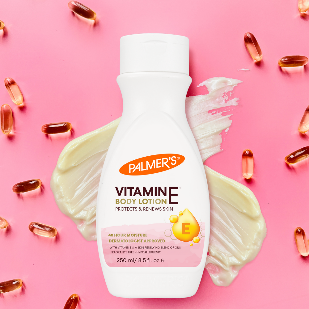 Palmer's Vitamine E body lotion bottle with pink background and scattered capsules.