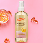 Palmer's Vitamin E oil bottle with capsules on a pink background