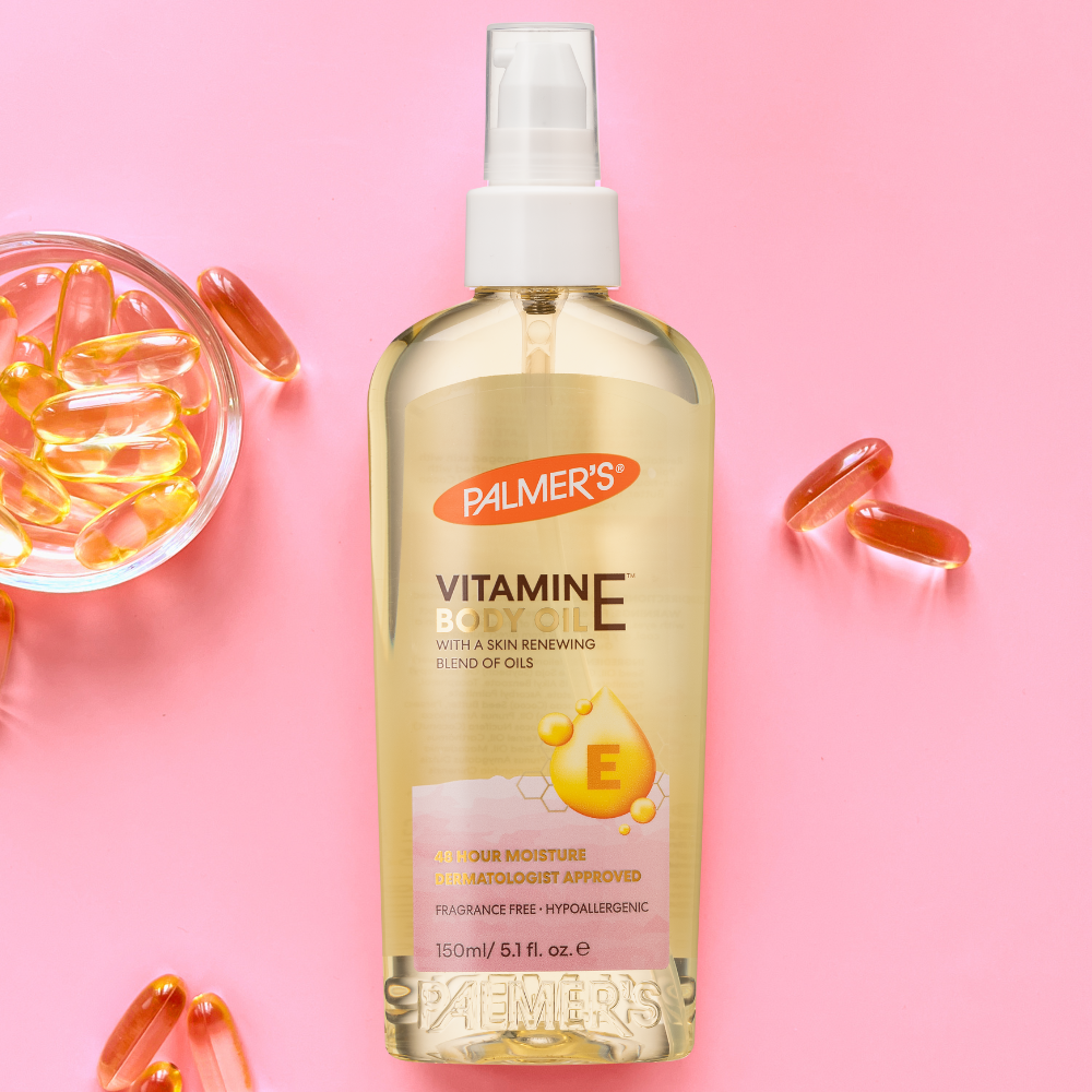 Palmer's Vitamin E oil bottle with capsules on a pink background