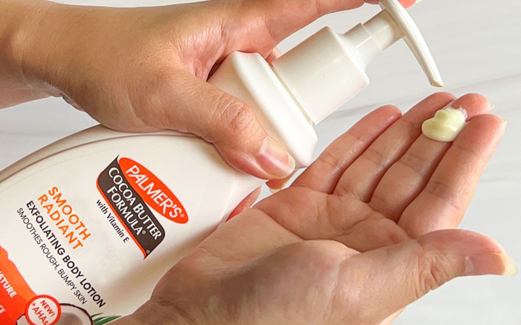 woman squeezing palmers exfoliating body lotion in to hand